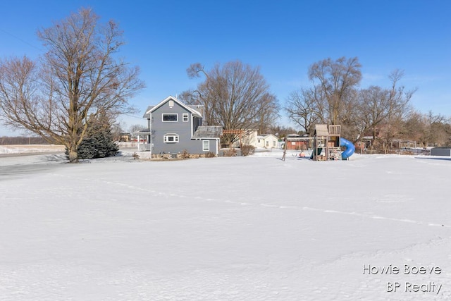 yard layered in snow featuring a playground