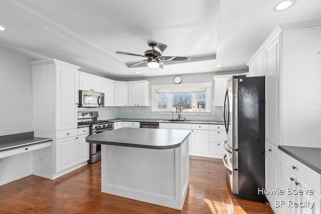 kitchen with a kitchen island, appliances with stainless steel finishes, white cabinets, and dark hardwood / wood-style flooring