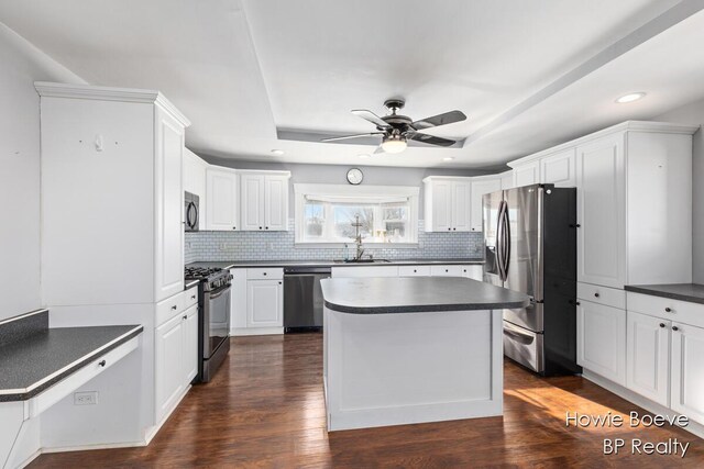 kitchen featuring sink, appliances with stainless steel finishes, white cabinetry, a center island, and dark hardwood / wood-style flooring