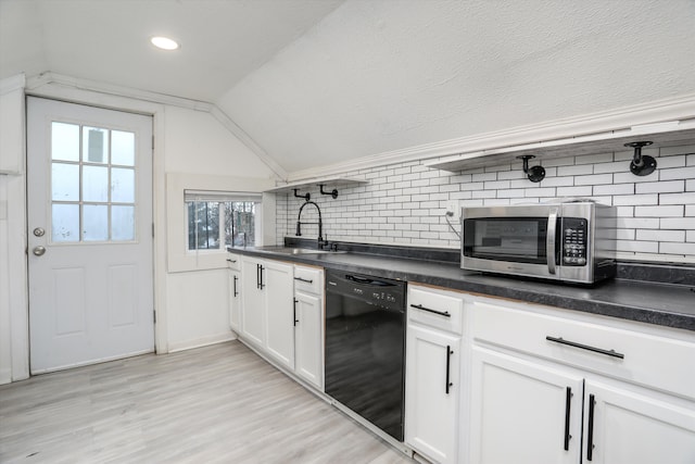 kitchen with vaulted ceiling, black dishwasher, sink, white cabinets, and light wood-type flooring