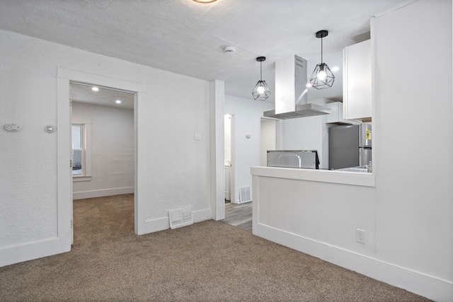 kitchen with stainless steel refrigerator, hanging light fixtures, island exhaust hood, carpet, and a textured ceiling