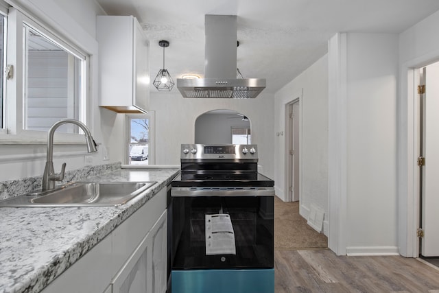 kitchen featuring sink, stainless steel electric range, island range hood, white cabinets, and decorative light fixtures