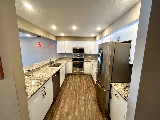 kitchen with sink, hanging light fixtures, appliances with stainless steel finishes, dark hardwood / wood-style floors, and white cabinets