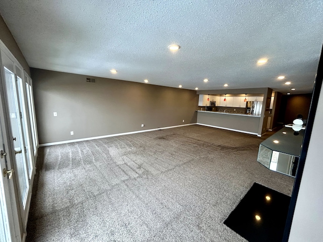 unfurnished living room featuring a textured ceiling and dark colored carpet