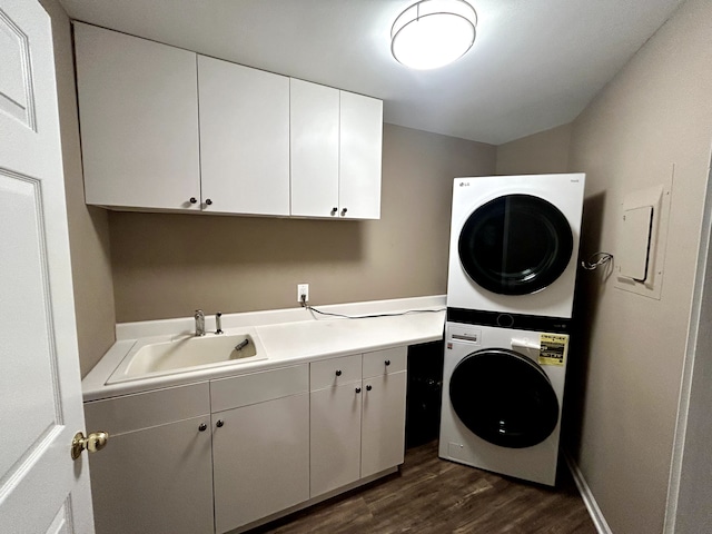 laundry area with cabinets, stacked washing maching and dryer, dark hardwood / wood-style flooring, and sink