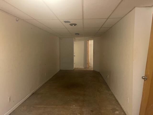 hallway featuring concrete flooring and a paneled ceiling