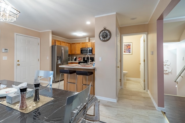 kitchen with crown molding, appliances with stainless steel finishes, and a center island with sink