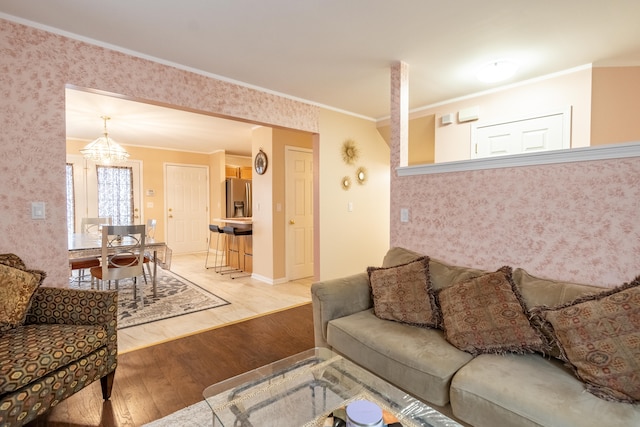 living room featuring hardwood / wood-style floors, crown molding, and a chandelier