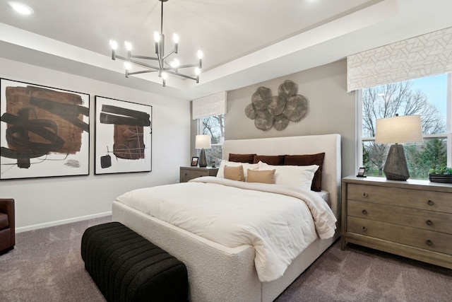 bedroom featuring dark colored carpet, an inviting chandelier, and a tray ceiling