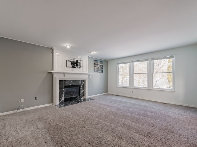 unfurnished living room with a premium fireplace and carpet