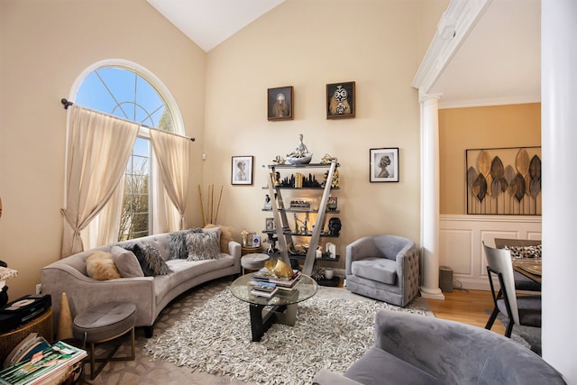 living room featuring decorative columns, wood-type flooring, and high vaulted ceiling