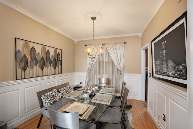 dining area featuring ornamental molding, an inviting chandelier, and light wood-type flooring