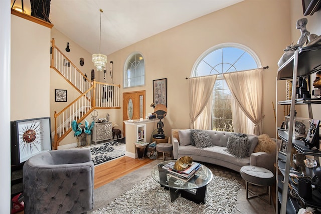 living room featuring an inviting chandelier, a towering ceiling, and hardwood / wood-style floors