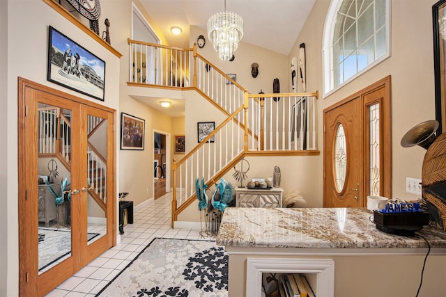 tiled foyer entrance featuring a notable chandelier, high vaulted ceiling, and french doors