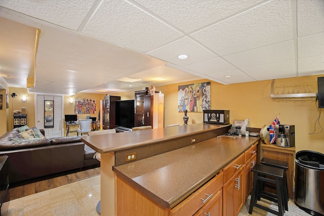 kitchen with crown molding, a breakfast bar area, and a drop ceiling