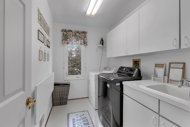 clothes washing area featuring cabinets, sink, and washing machine and clothes dryer