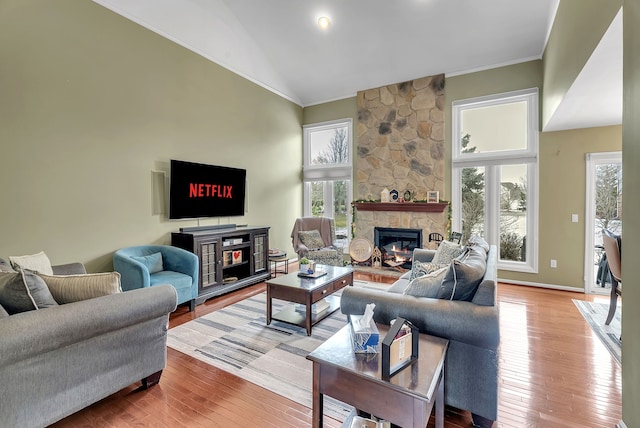 living room with hardwood / wood-style flooring, crown molding, high vaulted ceiling, and a fireplace