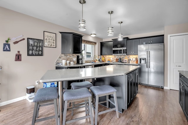 kitchen with backsplash, decorative light fixtures, a kitchen island, and appliances with stainless steel finishes