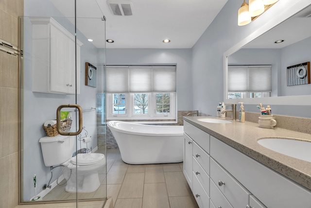 bathroom featuring vanity, a tub, tile patterned floors, and toilet