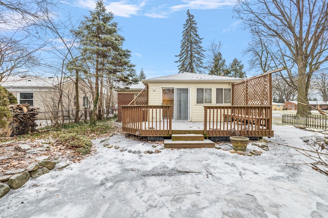 snow covered rear of property with a wooden deck