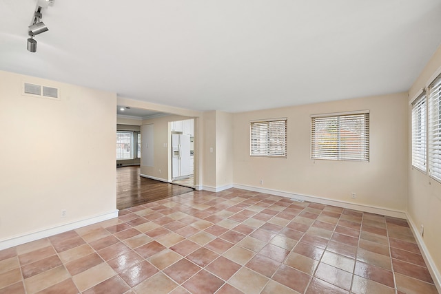 spare room with crown molding, track lighting, and light tile patterned floors