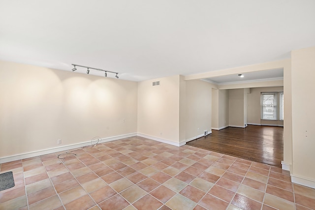 tiled spare room with ornamental molding and rail lighting