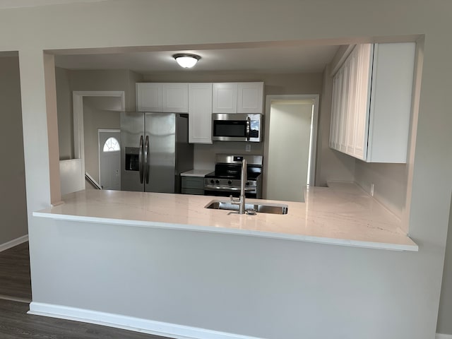 kitchen featuring white cabinetry, appliances with stainless steel finishes, kitchen peninsula, and dark wood-type flooring