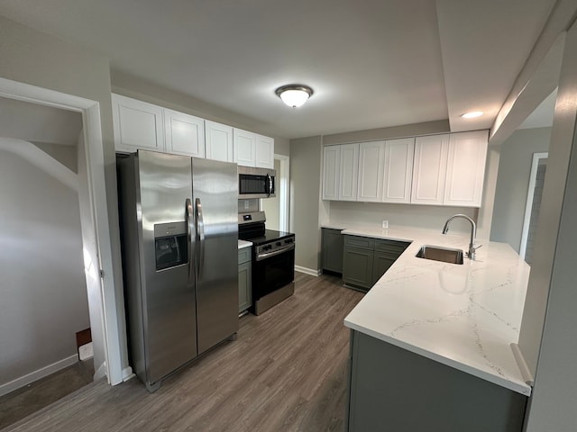 kitchen featuring sink, white cabinetry, dark hardwood / wood-style flooring, stainless steel appliances, and light stone countertops