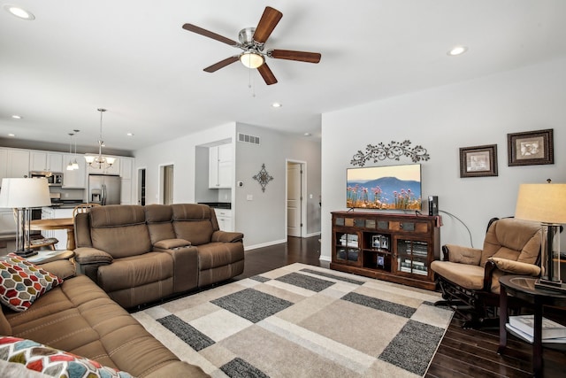 living room featuring ceiling fan with notable chandelier and dark hardwood / wood-style floors