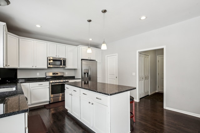 kitchen featuring hanging light fixtures, appliances with stainless steel finishes, a center island, and white cabinets