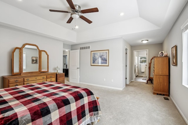 carpeted bedroom with ceiling fan and a tray ceiling