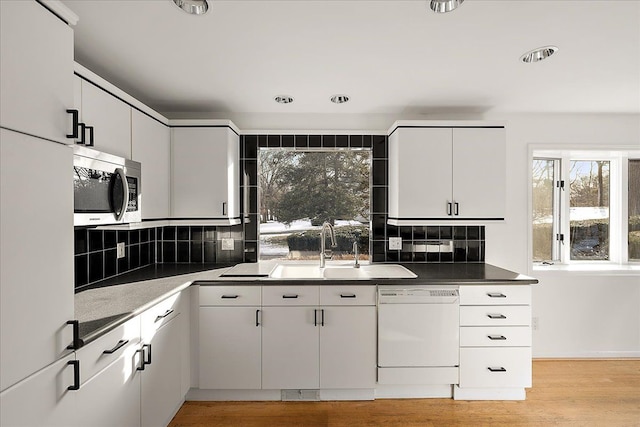 kitchen with sink, light wood-type flooring, backsplash, white cabinets, and white appliances