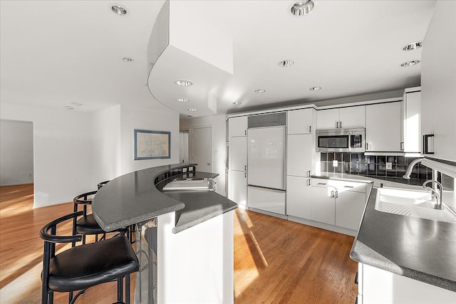 kitchen featuring paneled fridge, sink, hardwood / wood-style floors, and white cabinets