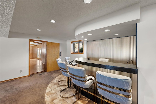 bar featuring light colored carpet and a textured ceiling