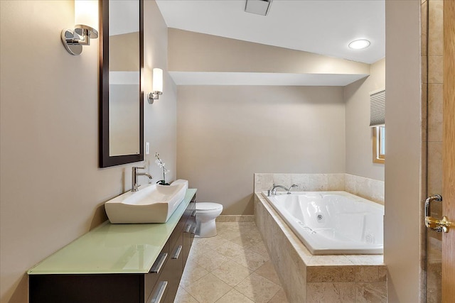 bathroom with a relaxing tiled tub, vanity, tile patterned floors, and toilet