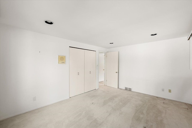 unfurnished bedroom with light colored carpet and a closet