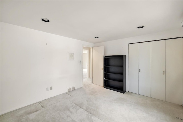 unfurnished bedroom featuring light colored carpet and a closet