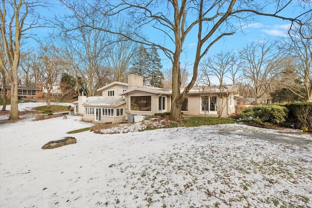 snow covered house featuring a sunroom