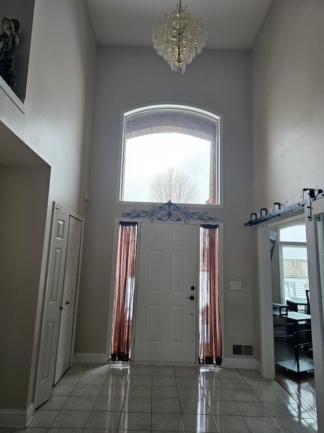 entrance foyer featuring a high ceiling, a barn door, light tile patterned floors, and a chandelier