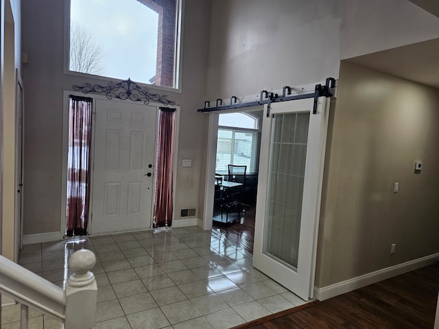 tiled entryway featuring a barn door and a high ceiling