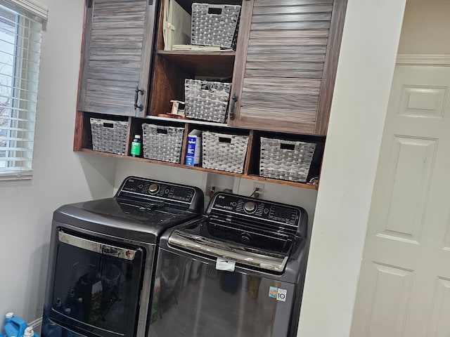 clothes washing area featuring washer and clothes dryer and cabinets