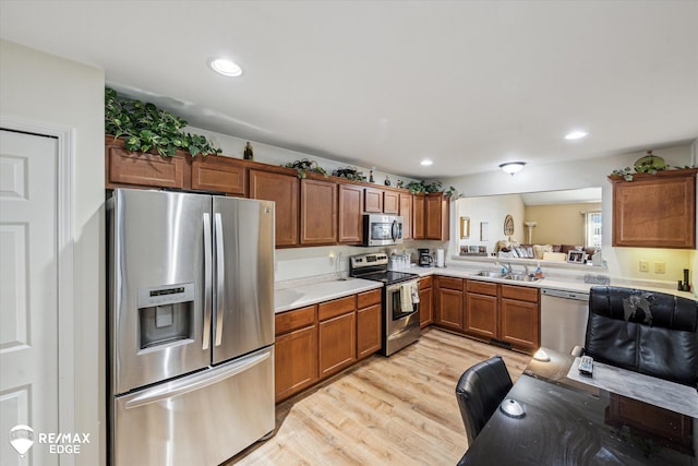 kitchen with stainless steel appliances, sink, and light hardwood / wood-style floors