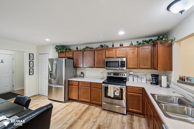 kitchen featuring appliances with stainless steel finishes, sink, and light wood-type flooring