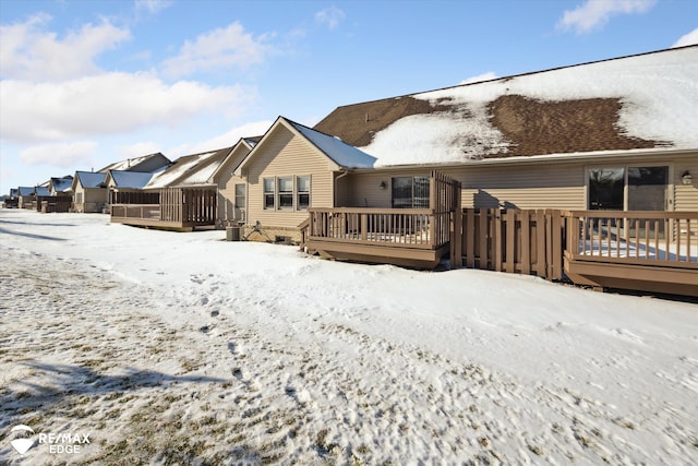 snow covered rear of property with a wooden deck