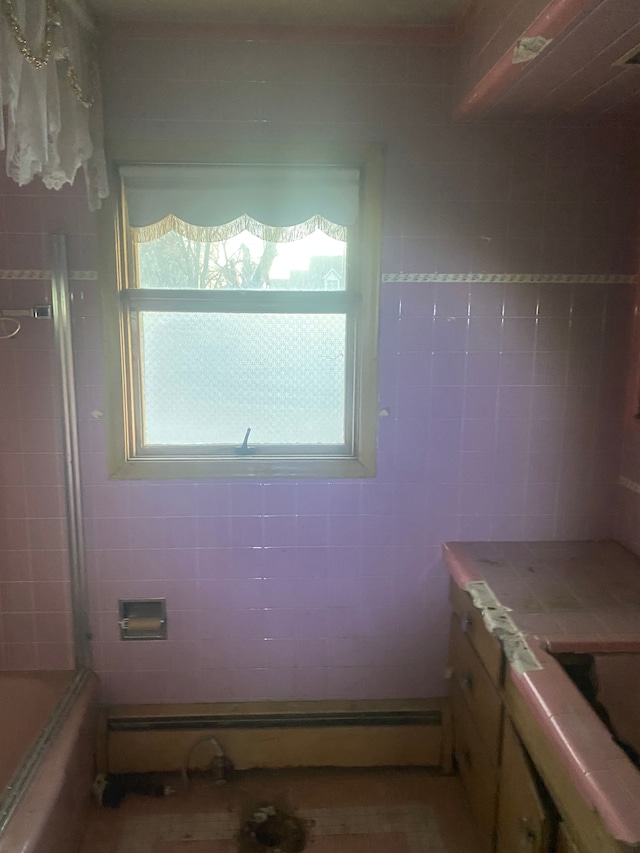 bathroom featuring vanity, a baseboard heating unit, tile walls, and shower / bath combination with glass door