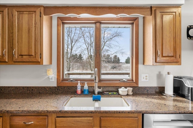 kitchen featuring dishwasher, light stone countertops, and sink