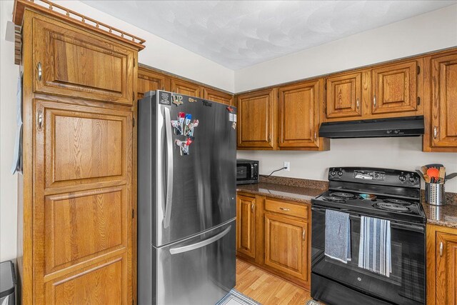 kitchen with stainless steel appliances, light hardwood / wood-style floors, and dark stone countertops