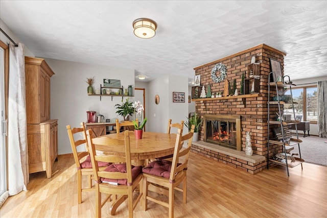 dining area featuring a fireplace, light hardwood / wood-style floors, and a textured ceiling