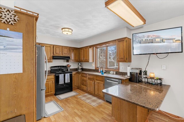 kitchen featuring sink, light wood-type flooring, kitchen peninsula, and appliances with stainless steel finishes