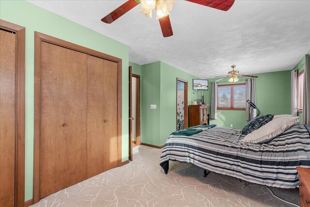 bedroom featuring two closets, light colored carpet, ceiling fan, and a textured ceiling